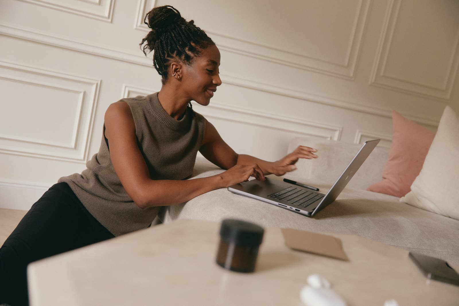 A smiling client using a laptop at home on a cream sofa